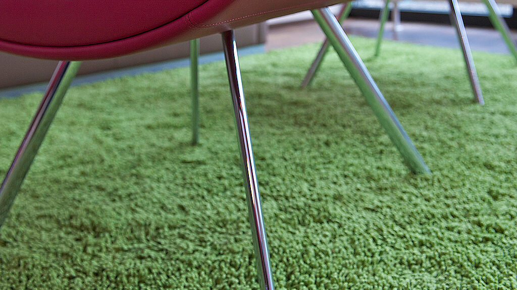 Roter Stuhl auf grünem Teppichboden