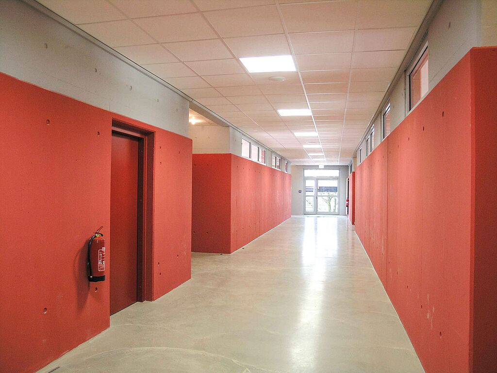 Flur in einem Verwaltungsgebäude mit rot gestrichenen Wänden und beigem PVC-Boden